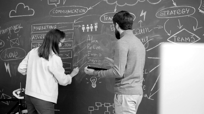 Early Stage Two people collaborating on a chalkboard with diagrams.
